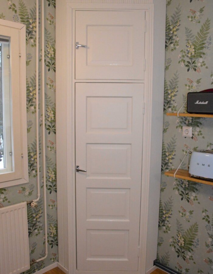 Valkoinen kulmakomero, vasemmalla ikkuna, taustalla värikäs tapetti. Asunto Järvenpäässä.